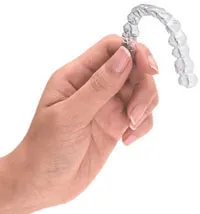 Photo: a hand holding Invisalign clear aligner appliance