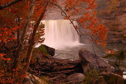 Fall landscape photo of a waterfall, rocks, and trees with orange leaves near Somerset KY